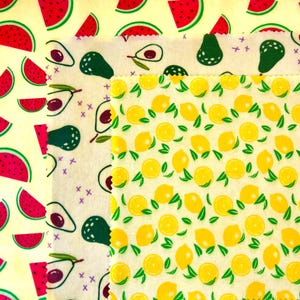 May include: Three pieces of patterned fabric. One features red watermelon slices on a yellow background. Another has avocado illustrations on a white background. The third displays yellow lemons with green leaves on a white background.