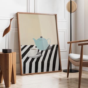 Può includere: Una stampa artistica incorniciata con una teiera azzurra, una tazza e un piattino bianchi e una tovaglia a righe bianche e nere. Lo sfondo è di colore beige chiaro. L'opera d'arte è in una cornice di legno.