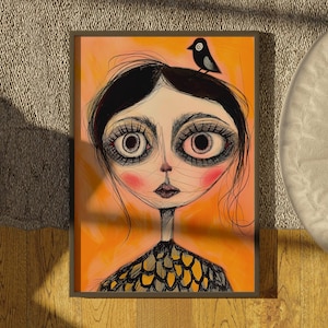 Könnte beinhalten: Gerahmter Kunstdruck mit einem stilisierten Porträt mit großen Augen, rosigen Wangen und einem kleinen Vogel auf dem Kopf. Das Kunstwerk hat einen skurrilen, folkloristischen Stil mit einem schwarz-gelb gemusterten Oberteil vor orangefarbenem Hintergrund.