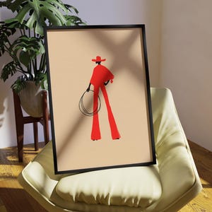 May include: Framed art print featuring a stylized illustration of a figure in red attire, including a hat and flared pants, holding a lasso. The artwork is set against a beige background within a black frame, creating a bold visual statement.
