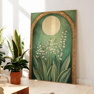 May include: A framed art print featuring a botanical illustration of lily of the valley flowers. The artwork has a green and gold color scheme, with a large moon shape in the background. The frame is gold.
