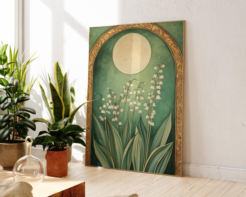 May include: A framed art print featuring a botanical illustration of lily of the valley flowers. The artwork has a green and gold color scheme, with a large moon shape in the background. The frame is gold.
