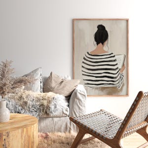 May include: A black and white striped illustration of a person sitting and reading a book. The illustration is framed in a light wood frame and is set against a light beige background.