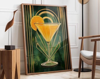 May include: A framed art print featuring a cocktail with an orange slice garnish. The artwork has a green and gold Art Deco design. The frame is a dark wood color. The print is leaning against a white wall.