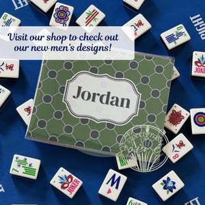 May include: A personalized green and gray Mahjong tile case with the name "Jordan" in white, surrounded by Mahjong tiles on a blue surface. The tiles have various symbols and numbers. Text on the image reads "Visit our shop to check out our new designs!"