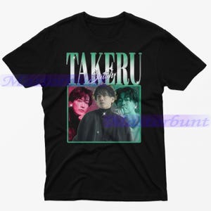May include: Black t-shirt with a vintage-style graphic of the Japanese actor,  Takeru Satoh. The graphic features three images of Satoh in different poses, with a green, pink, and blue color scheme.
