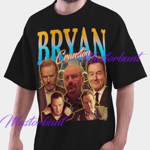 May include: Black t-shirt featuring a graphic of Bryan Cranston with the name "BRYAN Cranston" in a gradient blue and yellow font. The graphic includes multiple images of the actor. The shirt is a crew neck.