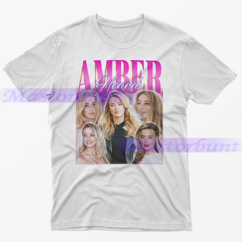 May include: White t-shirt featuring a pink and purple graphic with the name "AMBER Heard" and multiple images of a woman. The design is centered on the front of the shirt.