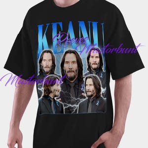May include: Black t-shirt featuring a graphic of Keanu Reeves with the name "Keanu" in blue block letters. The design includes multiple images of the actor with lightning bolt accents.