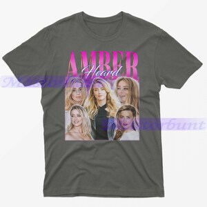 May include: Gray t-shirt featuring a collage of images of Amber Heard with the name "AMBER Heard" in a pink and purple gradient font. The shirt is a crew neck style.