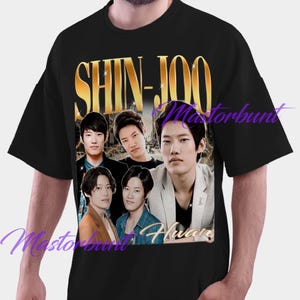 Puede incluir: Camiseta negra con la inscripción dorada "SHIN-JOO" y una foto de cinco hombres. La imagen tiene un aspecto vintage y ligeramente descolorido. Los hombres visten chaquetas y vaqueros. El diseño general es ligeramente envejecido.