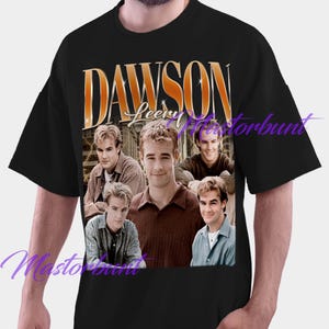 May include: Black t-shirt featuring a vintage-style graphic with the text "DAWSON" in gold lettering. The graphic includes multiple images of a man. The shirt is a classic crew neck style.