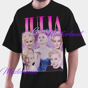 以下が含まれることがあります： ジュリア・ガーナーの画像をコラージュした黒いTシャツ。ピンク色の「JULIA」と白色の「Garner」の文字が入っています。Tシャツはクルーネックで半袖です。