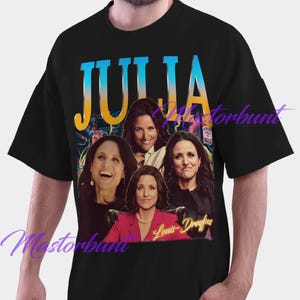 May include: Black t-shirt featuring a graphic of Julia Louis-Dreyfus with the name "JULIA" in blue and yellow text. The graphic includes multiple images of the actress. The text "Louis-Dreyfus" is also present.