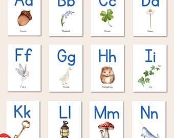 May include: A set of alphabet flashcards featuring watercolour illustrations of various objects. Each card has a letter in blue and the name of the object below. The objects include an acorn, bluebell, clover, daisy, egg, fairy, goose, hedgehog, ivy, juniper, key, lantern, mushroom, narwhal, and oak.