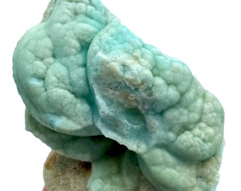 May include: A cluster of blue-green celestite crystals with a bubbly, textured surface. The crystals are clustered together in a natural formation.