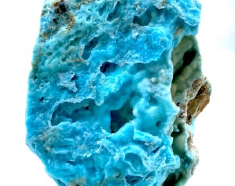 May include: A large, blue, and white, geode with a rough, textured surface. The geode has many holes and cavities throughout the surface.