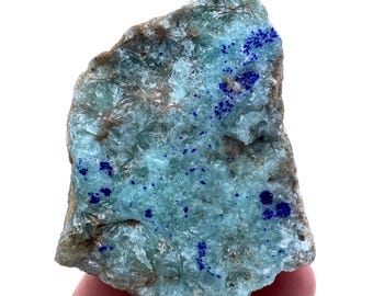 May include: A rough, light blue and brown crystal with blue specks. The crystal has a unique, textured surface.