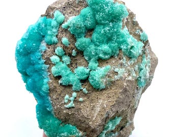 May include: A large rock with a cluster of bright green and blue mineral formations. The rock is covered in a variety of green and blue crystals.