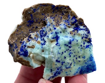 May include: A rough, brown rock with a light blue and white mineral deposit. The mineral has a speckled appearance with blue flecks throughout.