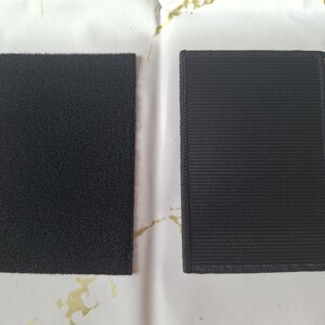 May include: Two black rectangular hook and loop fastener patches. One patch has a fuzzy surface, and the other has a woven texture with a stitched border. These are commonly used for attaching items.