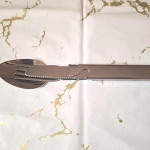 以下が含まれることがあります： シルバーの多機能カトラリーセット。スプーン、フォーク、ナイフが含まれており、すべて接続されており、コンパクトに収納できるように折りたためます。このカトラリーはステンレス鋼製で、屋外での使用を目的としています。