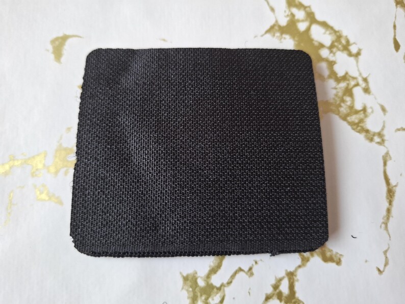 May include: A black rectangular patch of fabric with a textured surface.