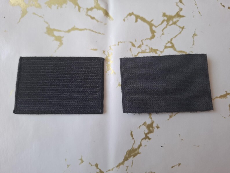 Peut inclure: Deux patchs rectangulaires en tissu gris fonc&eacute; avec une surface textur&eacute;e sont pr&eacute;sent&eacute;s sur un fond blanc avec des marbrures dor&eacute;es. Les patchs sont de taille et de forme similaires, sugg&eacute;rant qu'ils sont destin&eacute;s &agrave; un usage similaire.