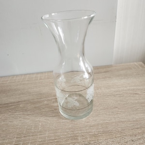 Peut inclure: Une carafe en verre transparent avec un motif de raisin blanc et une bande dorée au milieu.