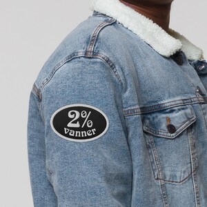 May include: A blue denim jacket with a white sherpa collar and a black oval patch that says "2% vanner" in white lettering.