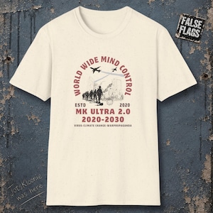 May include: A cream-colored short-sleeve t-shirt featuring a graphic print with the text WORLD WIDE MIND CONTROL, MK ULTRA 2.0, 2020-2030, and VIRUS-CLIMATE CHANGE-WARPROPAGANDA. The design includes silhouettes of soldiers, airplanes, and buildings.