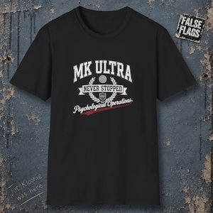 Può includere: Una t-shirt nera a maniche corte con una stampa grafica bianca che recita MK ULTRA NEVER STOPPED Psychological Operations, con un piccolo simbolo a scudo e una corona d'alloro. Una piccola toppa quadrata nell'angolo riporta FALSE FLAGS.