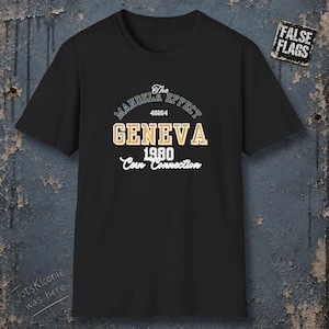 May include: A black short-sleeve t-shirt featuring a graphic print with the text The Mandela Effect, 46664, GENEVA, 1980, and Corn Connection. A small rectangular patch in the top right corner displays the text FALSE FLAGS in white on black.
