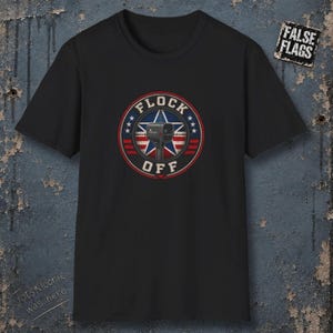 Peut inclure: Un t-shirt noir à manches courtes avec un motif circulaire comprenant une étoile rouge, blanche et bleue, une icône de caméra et le texte "FLOCK OFF". Un petit écusson rectangulaire en haut à droite affiche le texte "FALSE FLAGS".