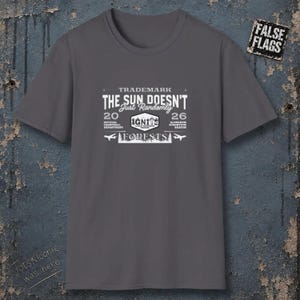 Peut inclure: Un t-shirt gris anthracite à manches courtes avec une impression graphique blanche. Le texte indique : TRADEMARK THE SUN DOESN'T Just Randomly 20 26 IGNITE OFFICIAL CHEMTRAIL DEPARTMENT ALUMINUM STRONTIUM BARIUM FORESTS. Un petit écusson indique FALSE FLAGS.