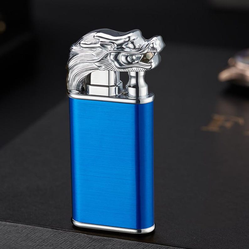 May include: A blue lighter with a silver dragon head design. The lighter has a brushed metal finish.