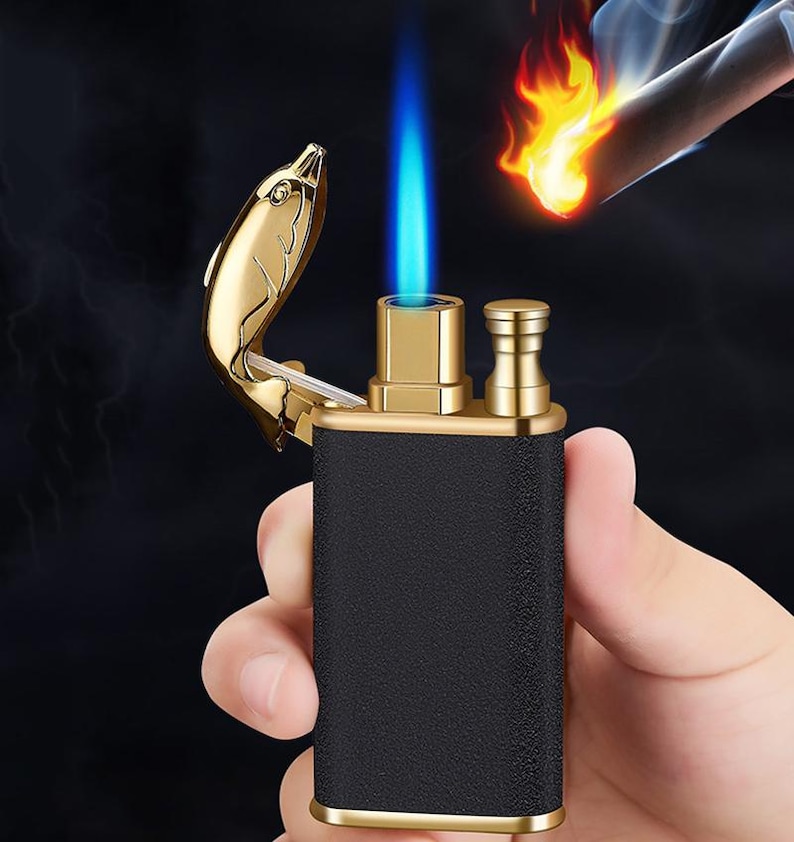 May include: A black and gold lighter with a dolphin-shaped lid. The lighter is lit and has a blue flame.