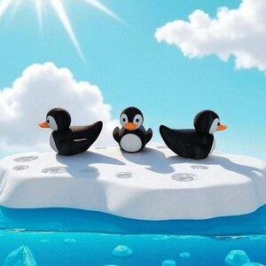 May include: Three penguin figurines on a white and blue iceberg, set against a bright blue sky with fluffy white clouds. The penguins are black and white with orange beaks, and the water below is a vibrant blue.