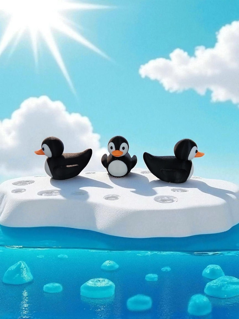 May include: Three penguin figurines on a white and blue iceberg, set against a bright blue sky with fluffy white clouds. The penguins are black and white with orange beaks, and the water below is a vibrant blue.