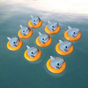 May include: Eight small gray shark figurines floating in orange life preservers on a blue water background.