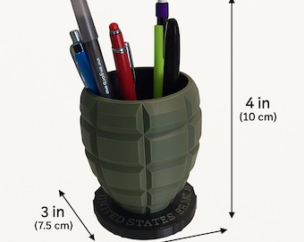 May include: A green desk organizer shaped like a grenade, 4 inches (10 cm) tall and 3.5 inches (9 cm) wide, holding pens and a marker. The base reads "UNITED STATES BRANC". The organizer contains a blue pen, a red pen, a green pen, a black pen and a gray marker.