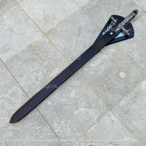 May include: A decorative sword with a silver handle and a red gem at the top. The sword is in a brown leather sheath. The sheath is attached to a black display stand. The sword is approximately 30 inches long.