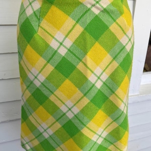 Puede incluir: Falda vintage hasta la rodilla con un vibrante estampado de cuadros en tonos verdes, amarillos y crema. La falda tiene una silueta recta y un diseño clásico, perfecta para un look retro o preppy. La falda mide unos 50 cm de largo.