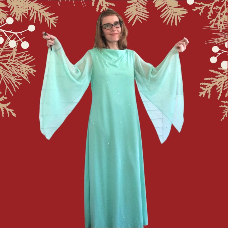 K&ouml;nnte beinhalten: Ein langes, flie&szlig;endes mintgr&uuml;nes Kleid mit hohem Ausschnitt und langen, weiten &Auml;rmeln. Das Kleid ist mit kleinen, wei&szlig;en Perlen verziert.