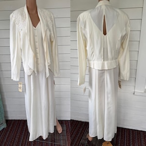 以下が含まれることがあります： アイボリー色のヴィンテージドレスと、お揃いのジャケット。ドレスはVネックのロング丈で、ジャケットは長袖で肩にレースがあしらわれています。白い背景にマネキンで展示されています。