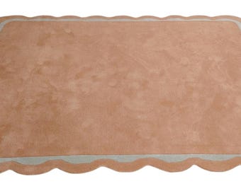 Op de afbeelding: Een rechthoekig tapijt met een geschulpte rand. Het tapijt heeft een lichtbruin midden met een lichtblauwe rand. Het tapijt is gemaakt van een zacht materiaal en is geschikt voor een woonkamer of slaapkamer.