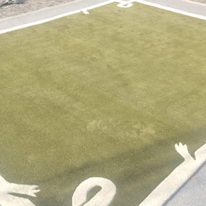 Op de afbeelding: Een groot, rechthoekig tapijt met een lichtgroen midden en een witte rand. De rand heeft decoratieve witte vormen in elke hoek. Het tapijt ligt op een grijze ondergrond, waardoor een gelaagd effect ontstaat. Het ontwerp van het tapijt voegt een vleugje elegantie toe.
