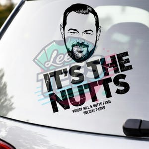 May include: A car window sticker with a black and white design. It features a man's face and the words "IT'S THE NUTTS" in a bold font. The sticker also includes the text "PRIORY HILL & NUTTS FARM HOLIDAY PARKS".
