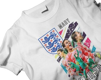 May include: White t-shirt featuring a graphic of the England national team crest and images of female soccer players. The word "MARY" is printed above the images. The design includes blue, pink, green, and purple accents.