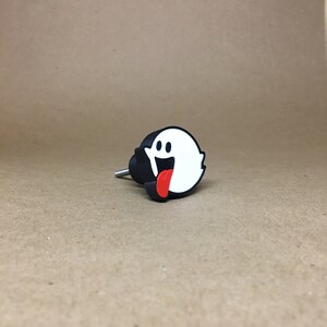 May include: Black and white ghost door knob with a red tongue sticking out.